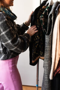 side profile of woman in pink pants and grey jacket touching clothing