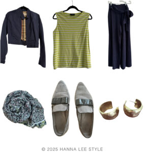 travel capsule wardrobe outfit example navy bomber jacket, sleeveless yellow stripe top, wide leg navy pant, floral blue scarf, neutral khaki pointed toe sneaker, gold hoop